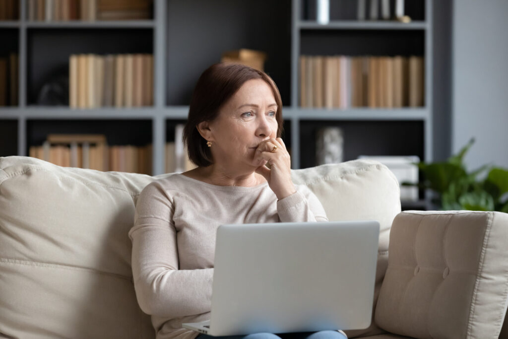 woman pondering anorgasmia causes in front of laptop