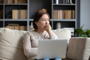 woman pondering anorgasmia causes in front of laptop